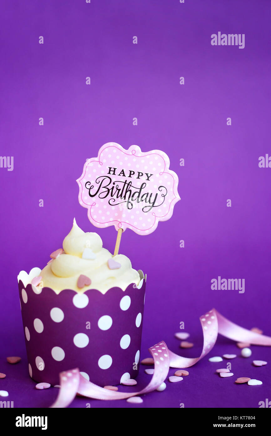 Cupcake avec de petits coeurs décoratifs et joyeux anniversaire signe, contre fond violet Banque D'Images