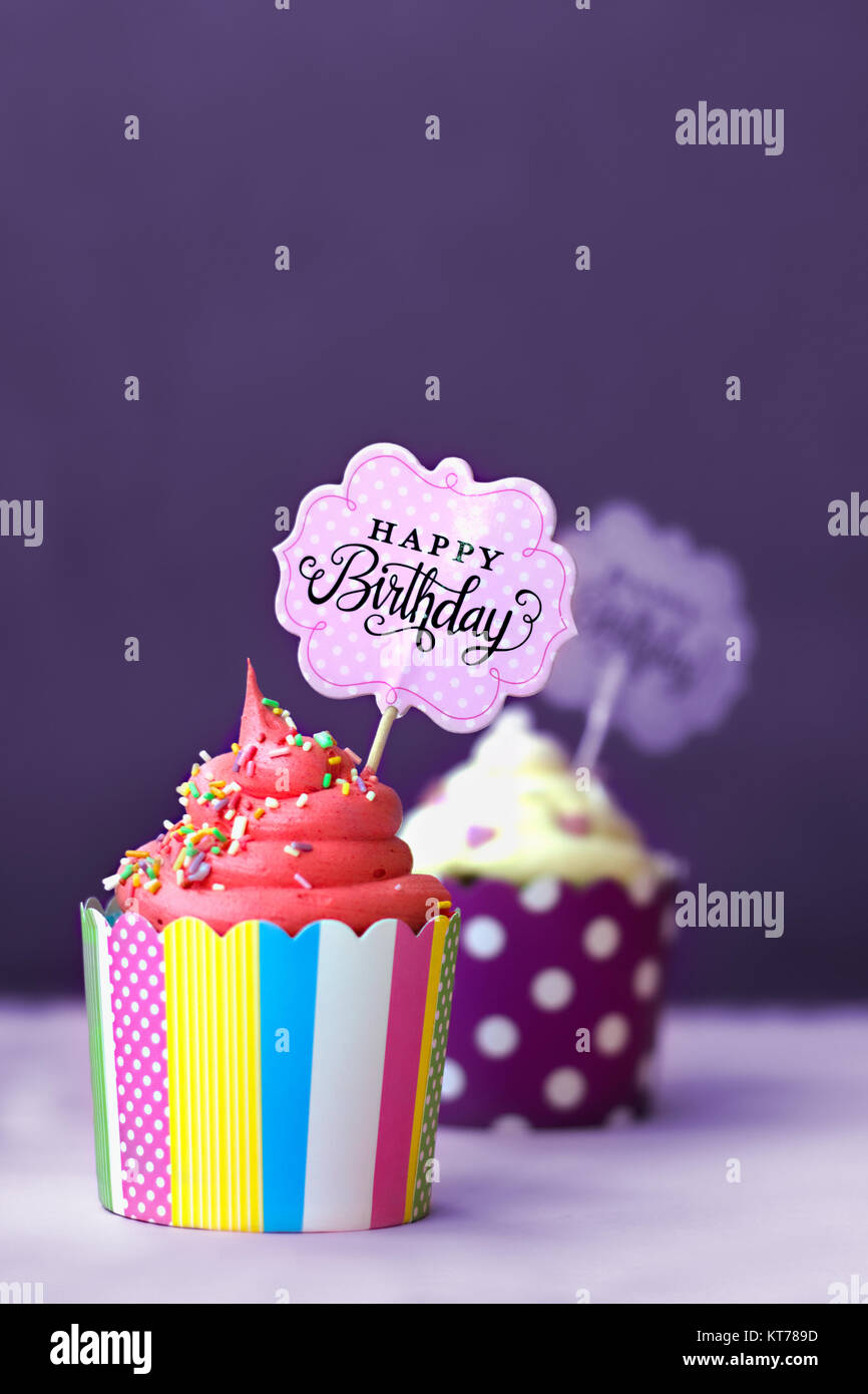 Fraise et vanille cupcakes avec petits coeurs décoratifs et joyeux anniversaire signe, contre fond violet ; party background Banque D'Images