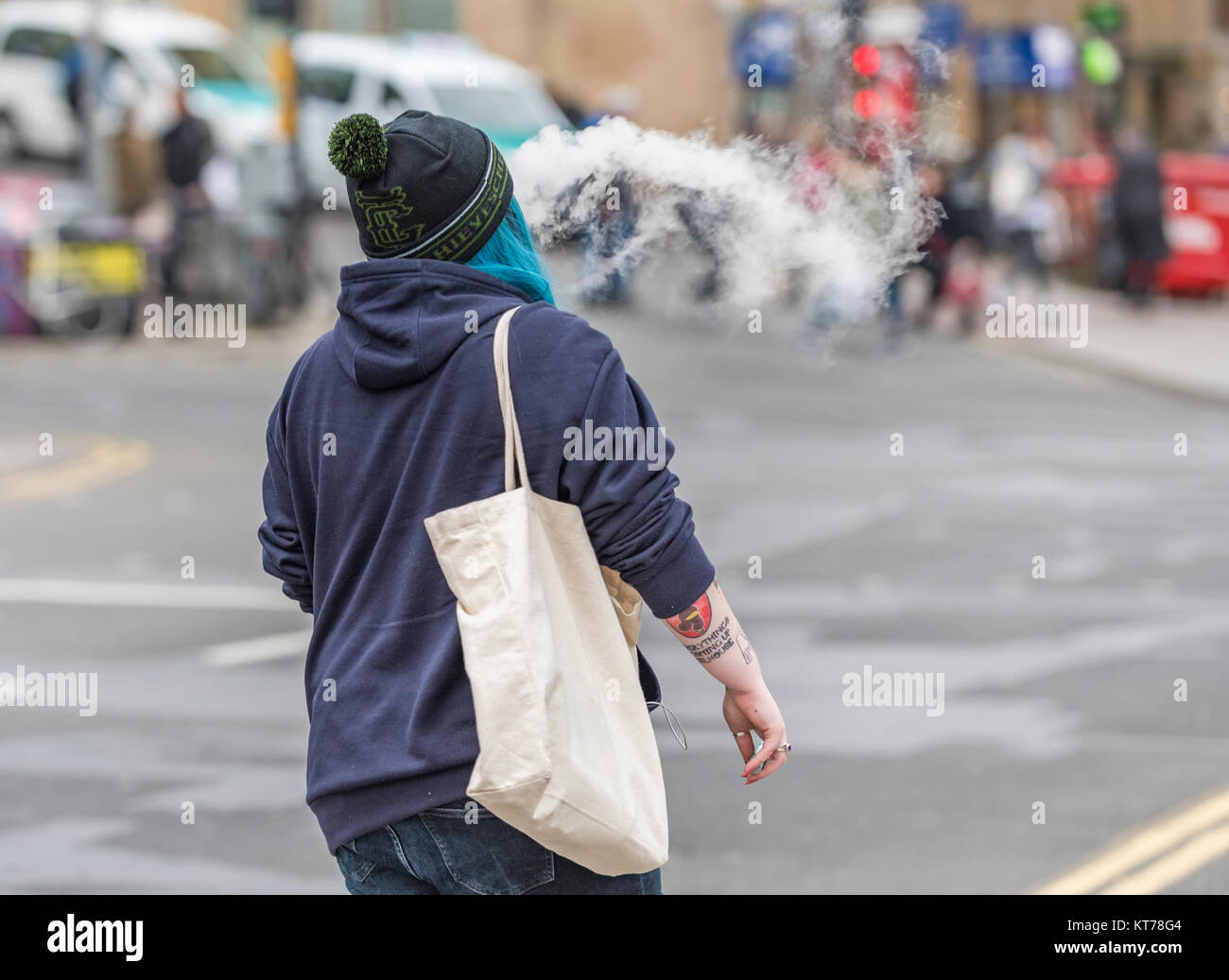 Une femme qui s'éloigne fumer une cigarette électronique, causant une fumée excessive, au Royaume-Uni. Banque D'Images Une femme qui s'éloigne fumer une cigarette électronique, causant une fumée excessive, au Royaume-Uni. Banque D'Images