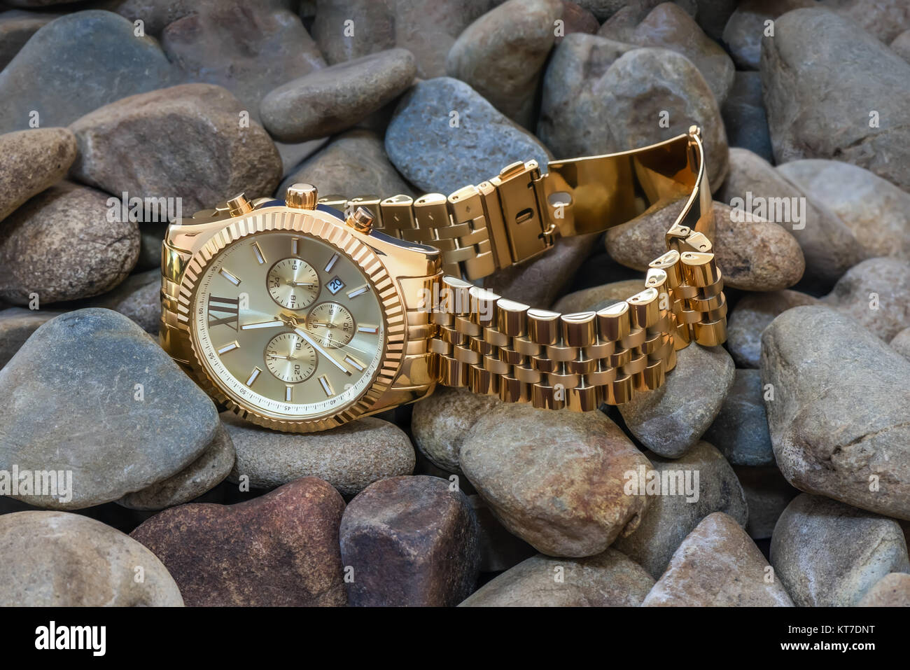 Close-up. Nouveau cher avec une montre en or bracelet métal jaune se trouvent sur des pierres grises Banque D'Images
