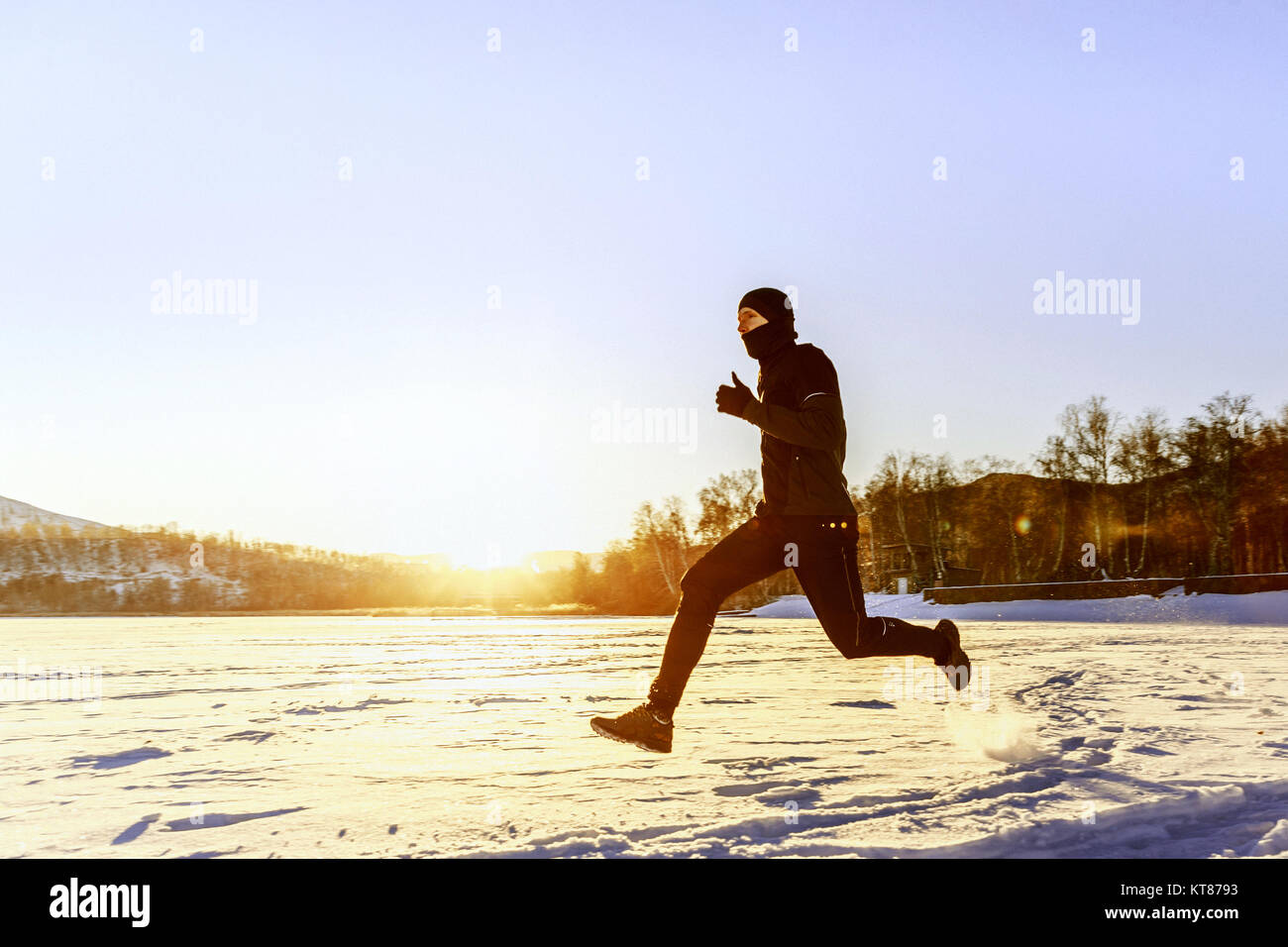Fonctionnement de l'athlète runner sur la neige dans les rayons du soleil Banque D'Images