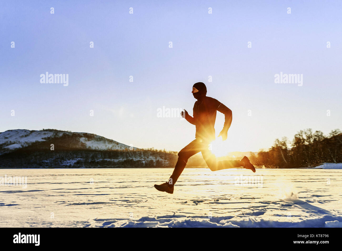 Homme de course d'hiver runner en arrière-plan de montagnes et le lever du soleil Banque D'Images