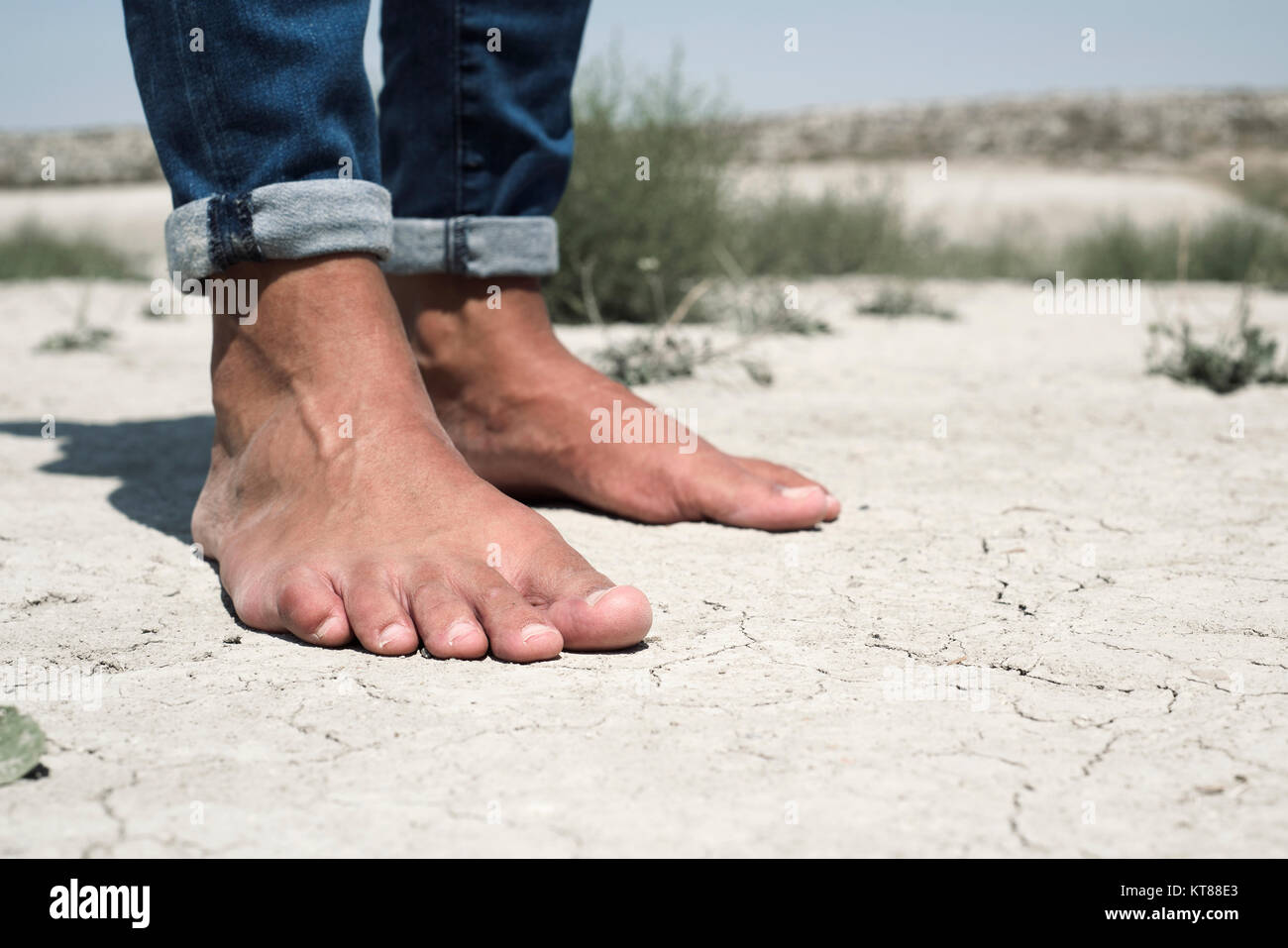 Gros plan des pieds nus d'un jeune homme de race blanche sur un sol sec  craquelé Photo Stock - Alamy