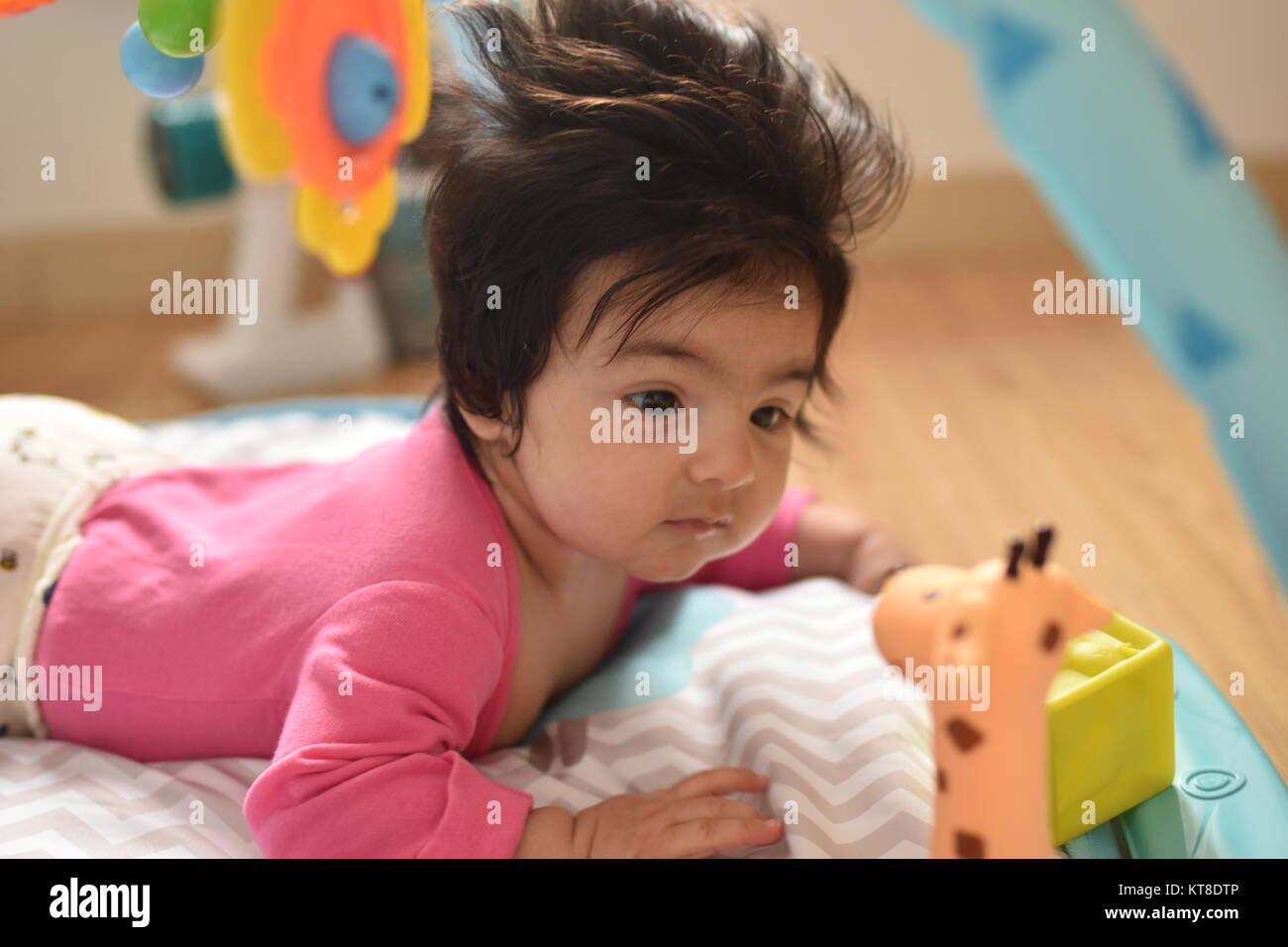Jolie petite fille aux cheveux longs regards attentivement ses jouets dans ses premières explorations Banque D'Images