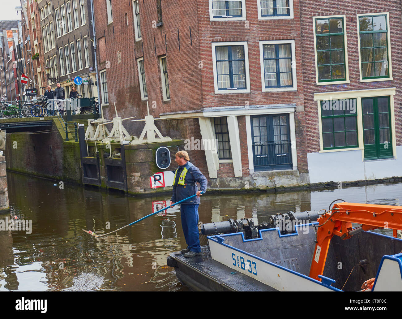 Homme debout sur le nettoyage de la litière de pêche Barge Canal, Amsterdam, Holland Banque D'Images