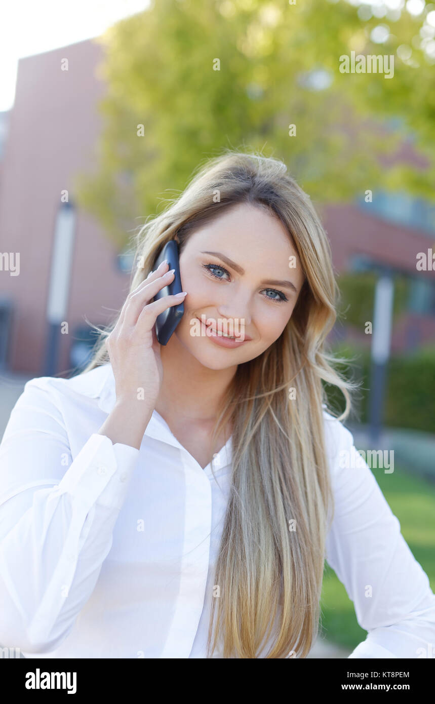 Certain blond businesswoman in shirt appelant, du quartier financier, extérieur Banque D'Images