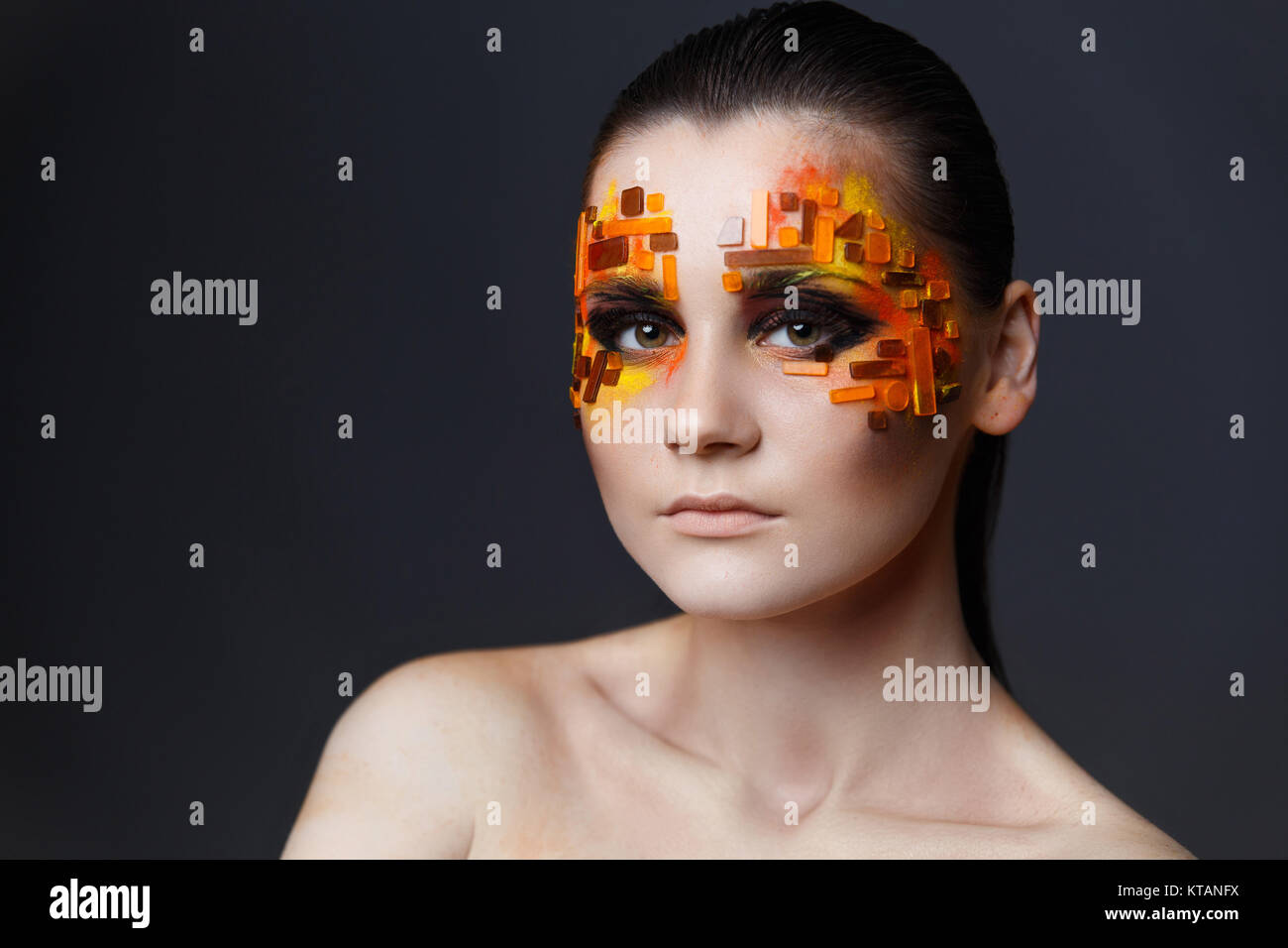 Fille avec strass orange et rouge sur son visage. Banque D'Images