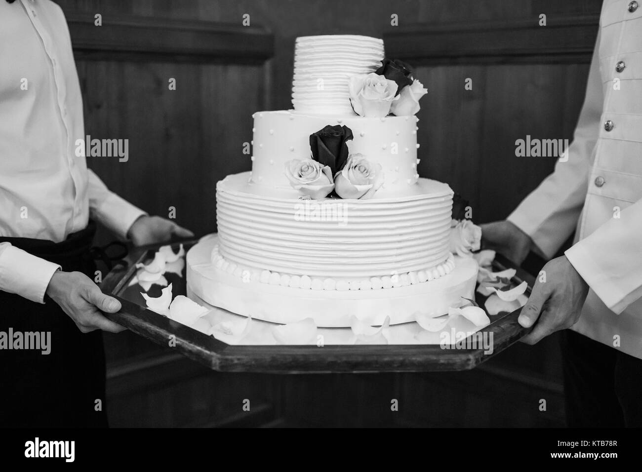 Gâteau de mariage blanc Multi de niveau sur une base et des fleurs sur le dessus. Banque D'Images