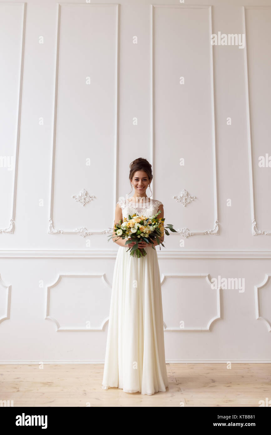 Bride holding bouquet mariage boho sur fond de mur blanc relief Banque D'Images