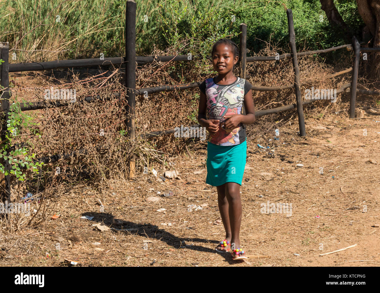 Une jeune fille malgache sourire sur un chemin de terre dans un petit village. Madagascar, l'Afrique. Banque D'Images