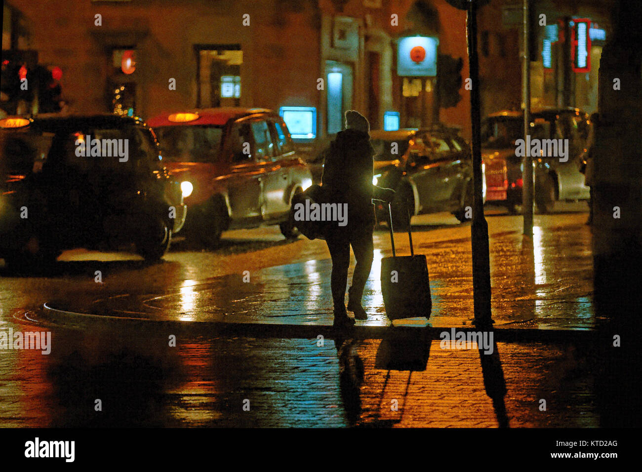 La nuit urbaine graveleuse humide Glasgow taxi rue femme ou fille de retour à la maison avec sac voyage girl à la station de bus la nuit seul près de Banque D'Images