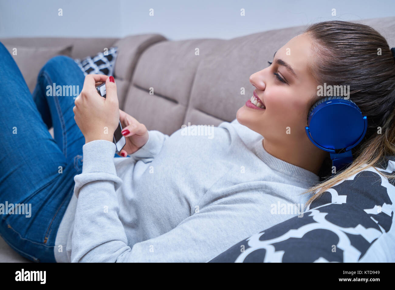 Jeune femme avec un casque à l'écoute de musique à la maison Banque D'Images