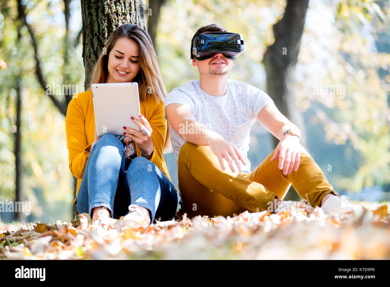 Couple assis dehors en utilisant divers tech gadgets, tablet, vr, concept Banque D'Images