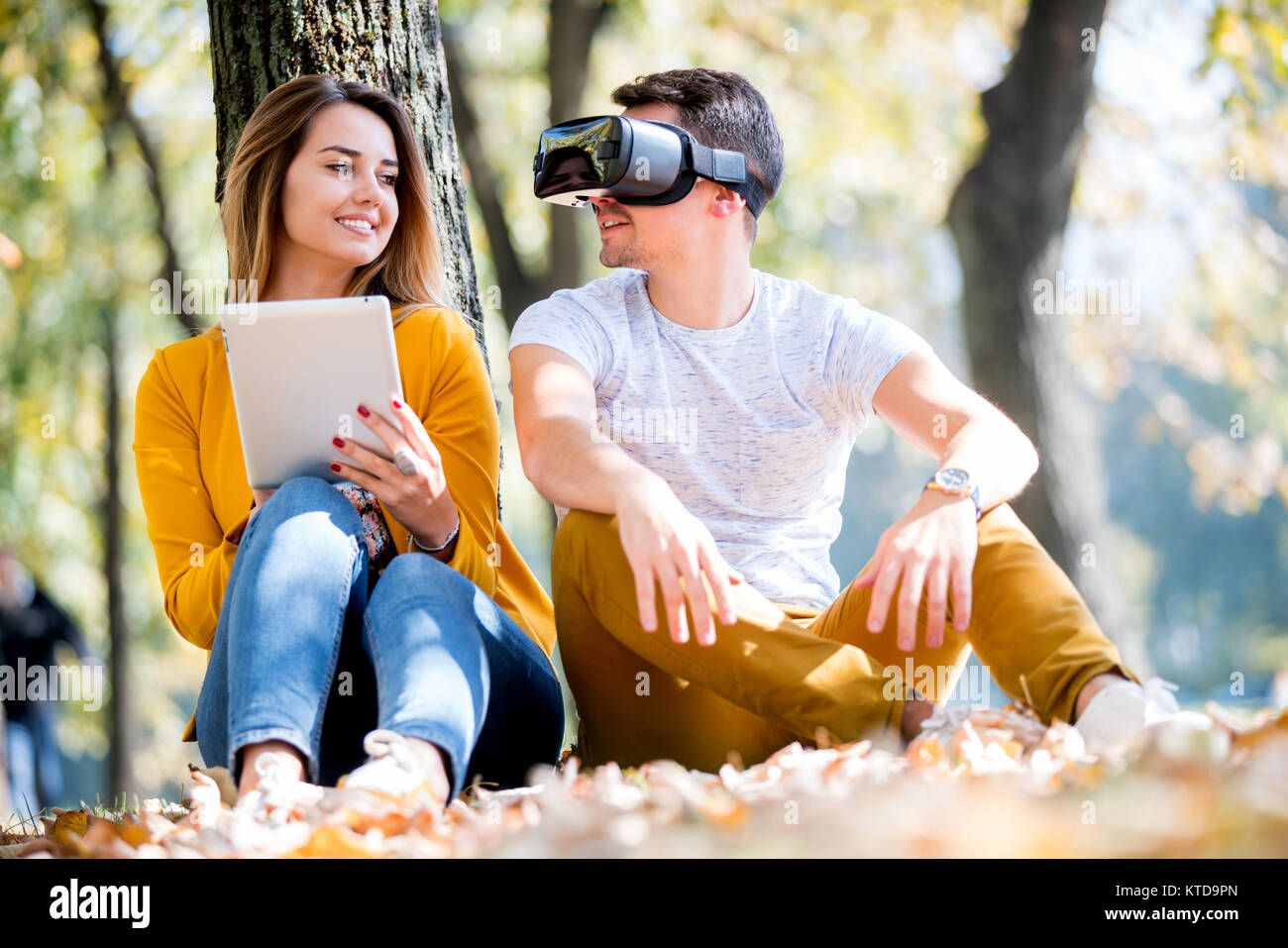 Couple assis dehors en utilisant divers tech gadgets, tablet, vr, concept Banque D'Images