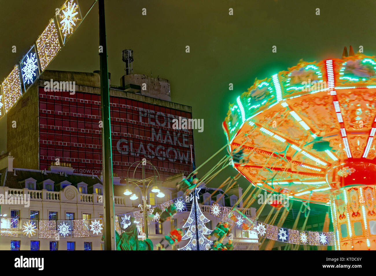 Pluie et vent saluer la dernière minute la veille de Noël Noël les visiteurs de la ville dans le fayre George square Glasgow à fond les gens font des balançoires Banque D'Images