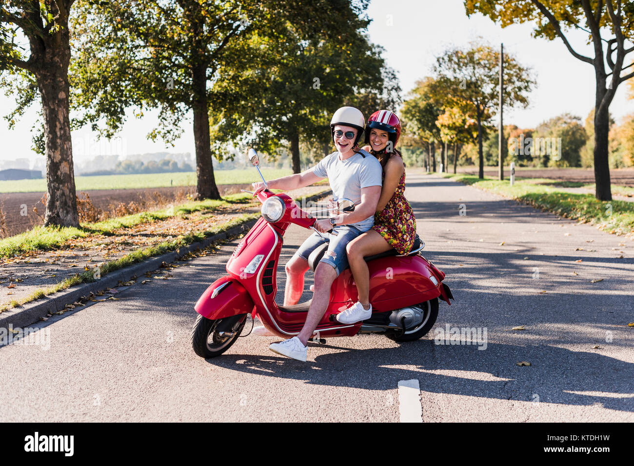 Portrait of happy young couple on motor scooter on country road Banque D'Images