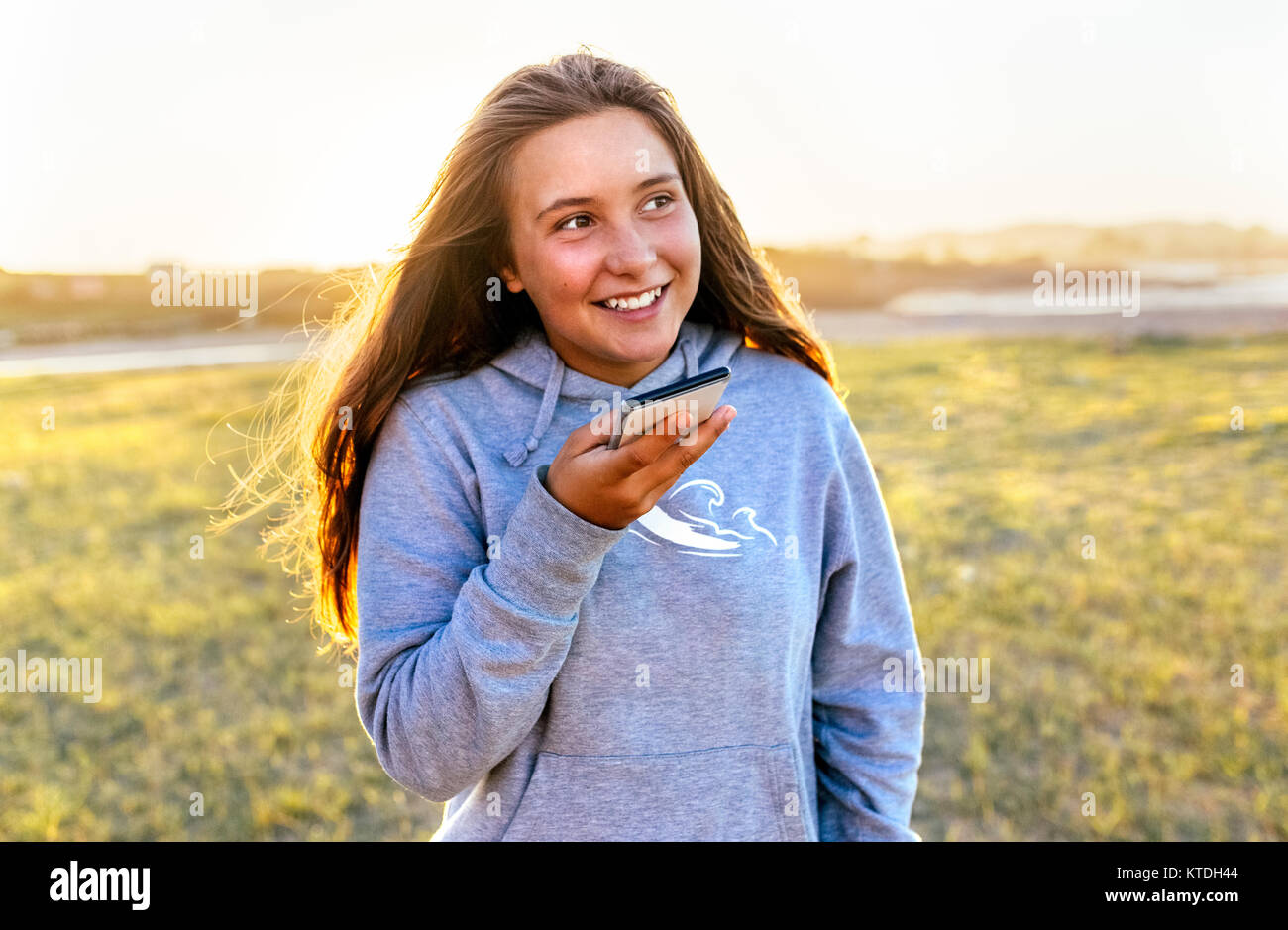 Portrait of smiling girl using cell phone outdoors Banque D'Images