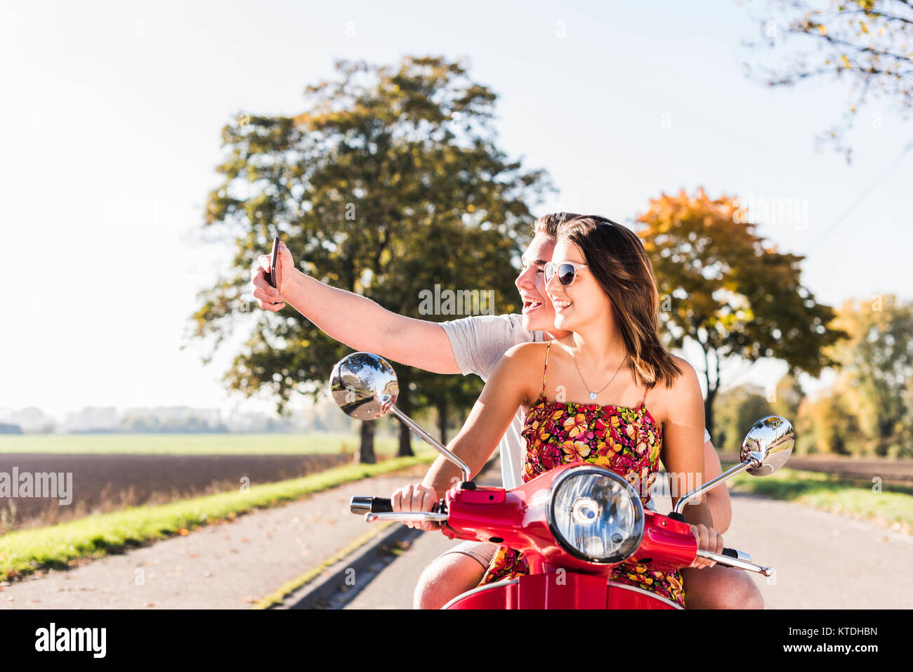 Couple de prendre un scooter sur selfies on country road Banque D'Images