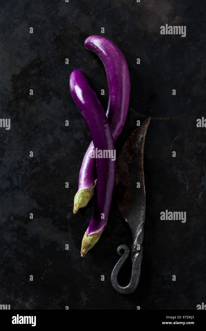 Deux Perlina aubergines et un vieux couteau sur la masse sombre Banque D'Images