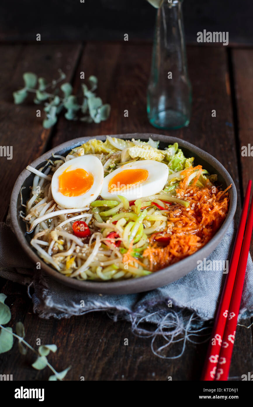 Bol de soupe de nouilles Udon sans gluten avec des carottes, chou chinois, germes de haricots mungo, zoodles et oeuf dur Banque D'Images
