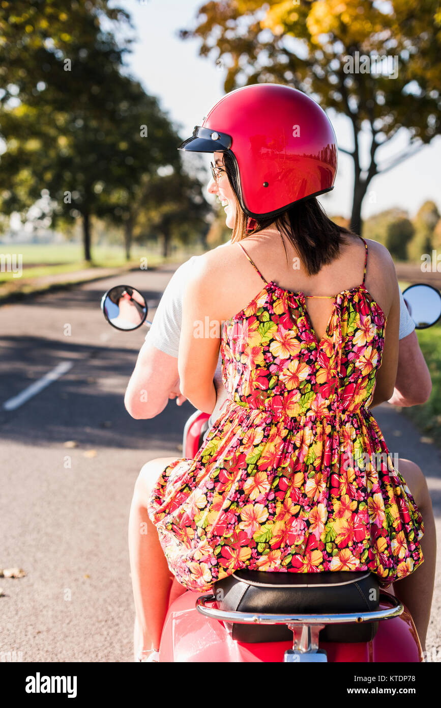 Jeune couple riding scooter on country road Banque D'Images
