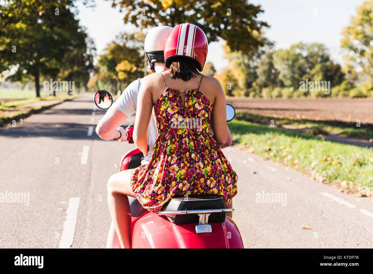 Jeune couple riding scooter on country road Banque D'Images