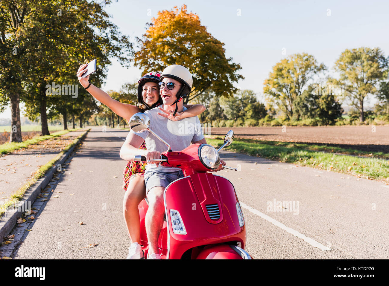 Couple de prendre un scooter sur selfies on country road Banque D'Images