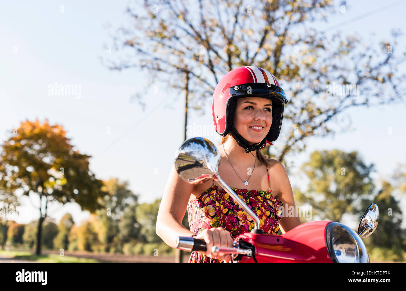 Portrait of smiling young woman on motor scooter Banque D'Images