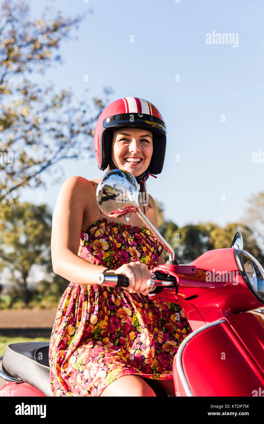 Portrait of happy young woman on motor scooter Banque D'Images
