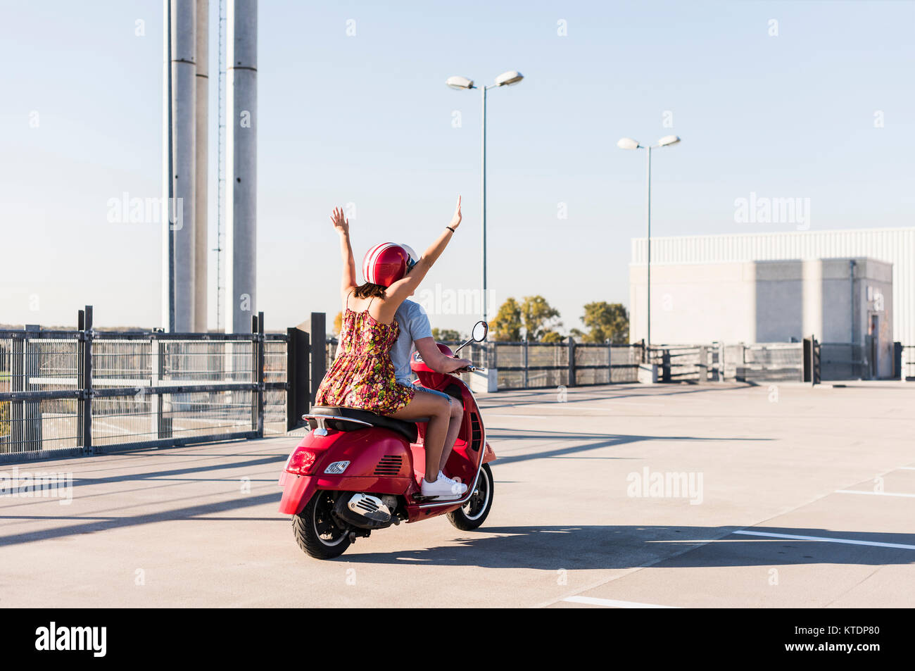 Carefree young couple riding scooter sur niveau parking Banque D'Images