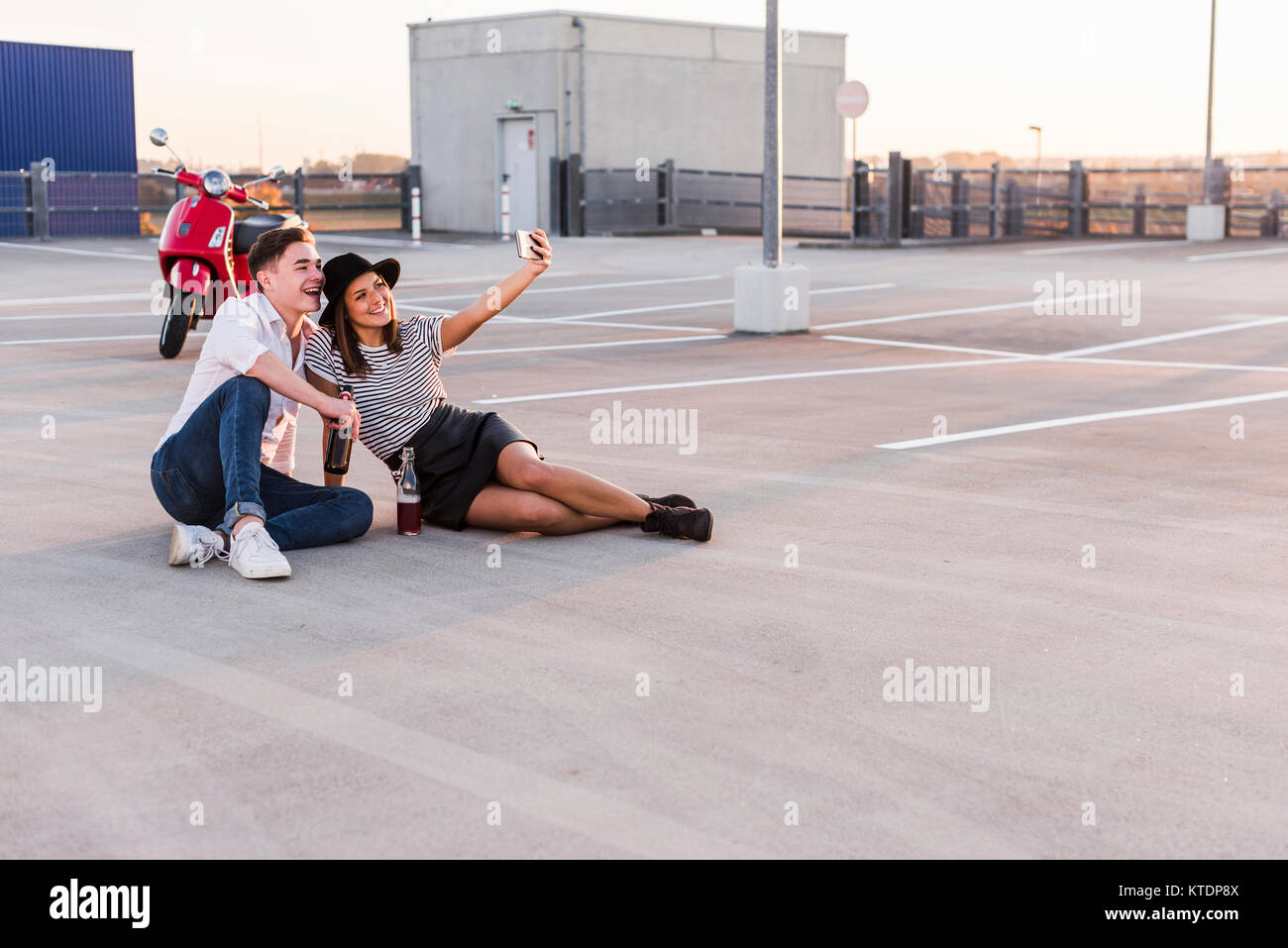 Happy young couple with scooter sur un niveau de parking selfies Banque D'Images