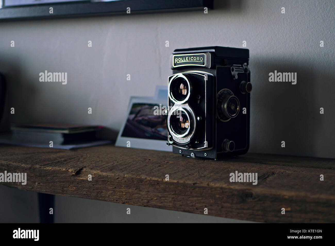 Un classique vintage appareil photo Rolleicord placé soigneusement sur une étagère en bois avec le soleil sur elle par le biais d'une grande fenêtre avec des photos à l'arrière. Banque D'Images