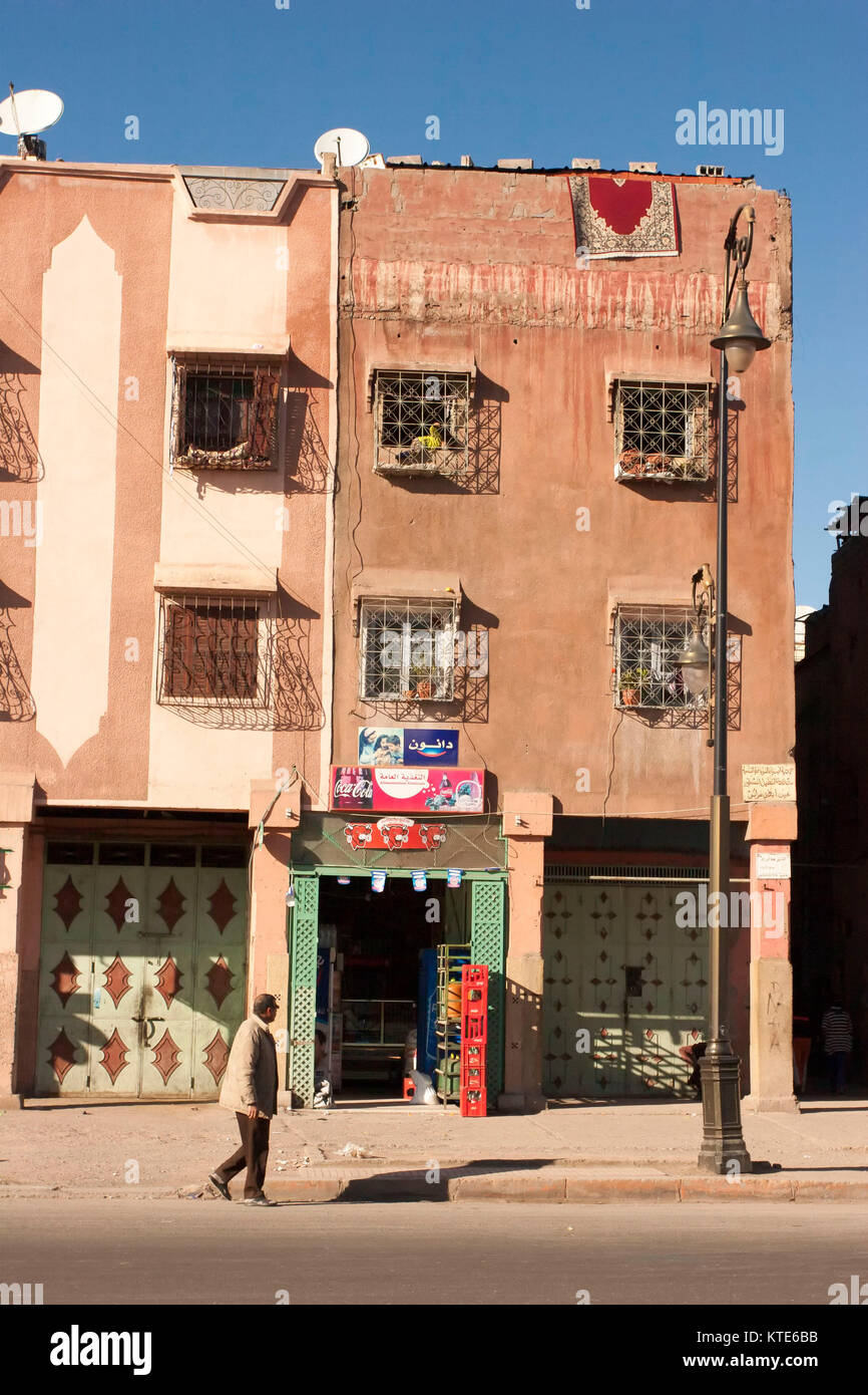 Homme marchant en face des appartements, Marrakech, Maroc Banque D'Images