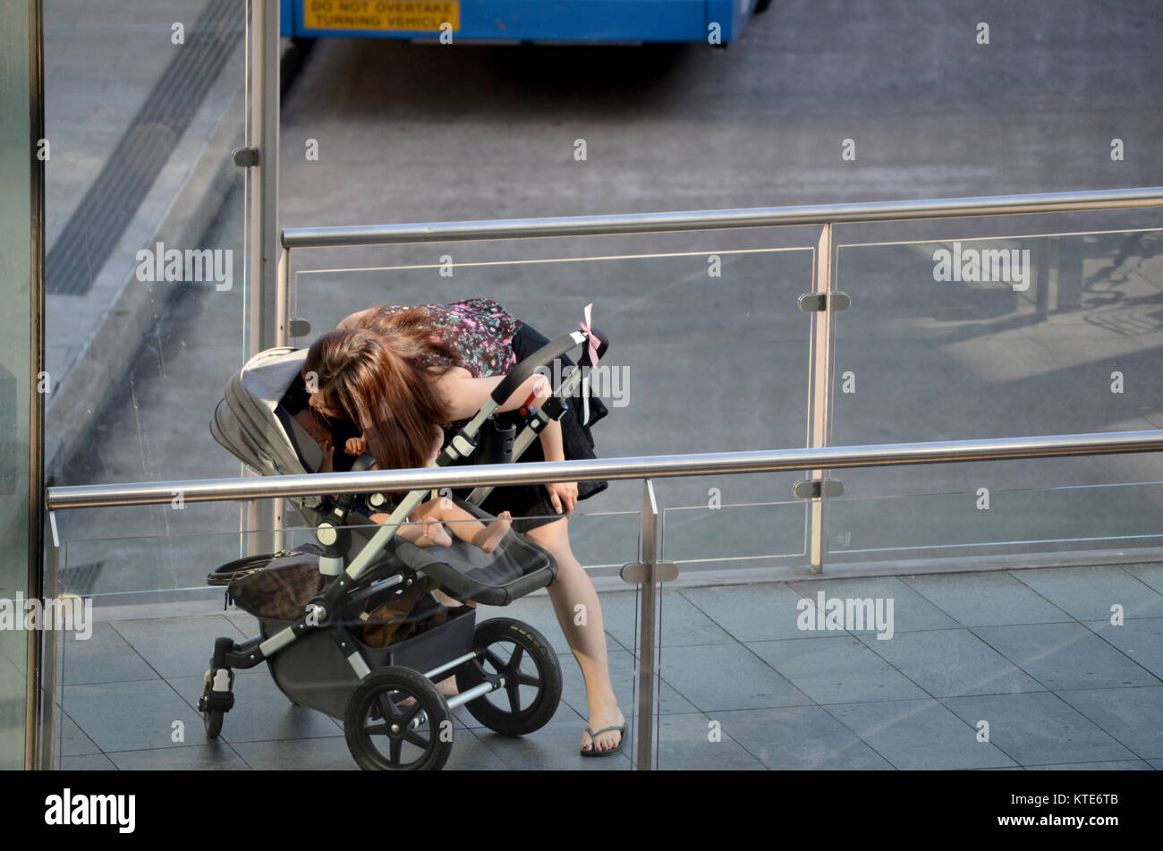 Jeune mère de famille dans la pram à la station de bus Banque D'Images