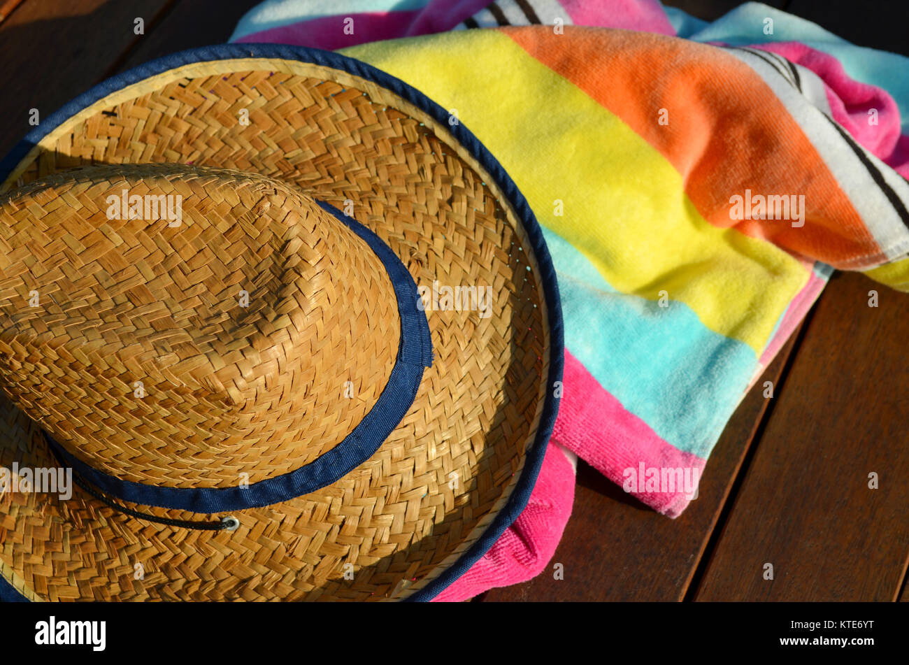 Plage de paille chapeau et serviette de plage rayée sur terrasse en bois Banque D'Images