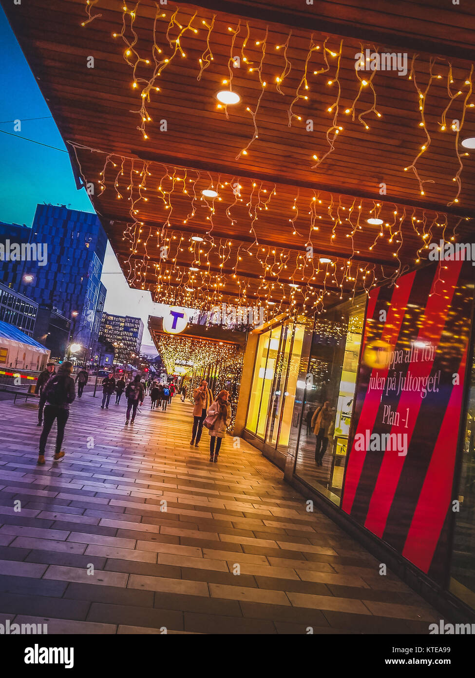 Les piétons qui se promènent dans un quartier commerçant avec des lumières de Noël décorant la devanture de la nuit, Stockholm, Suède Banque D'Images