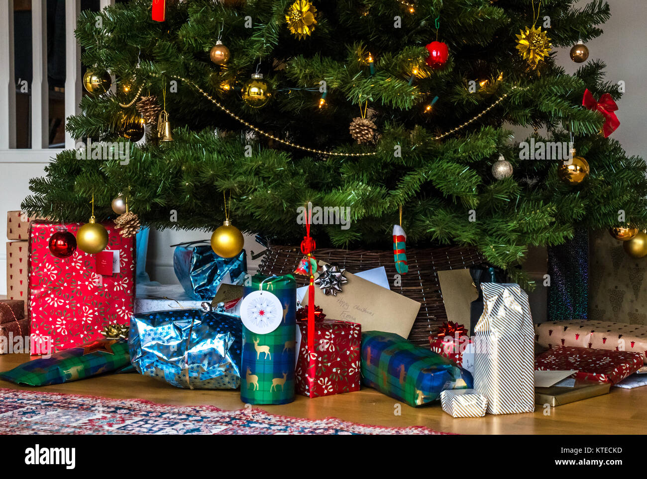 Enveloppé de Noël sous un arbre de Noël dans un salon familial avec un tapis persan Banque D'Images