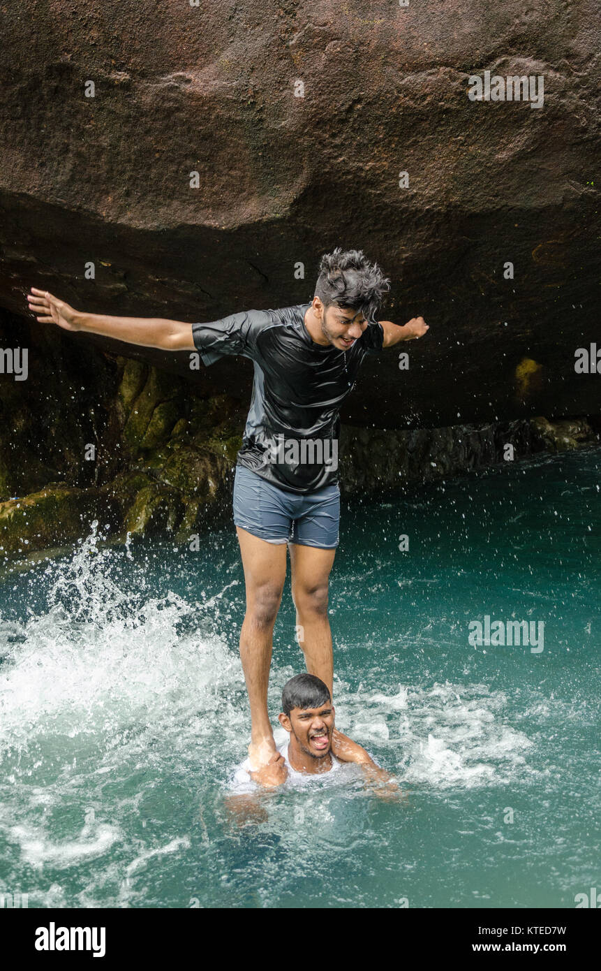 Garçon debout sur les épaules de l'autre, formant une tour humaine dans un bassin d'eau à Nagarmadi Chendia, chutes d'eau, Karnataka, Inde Banque D'Images