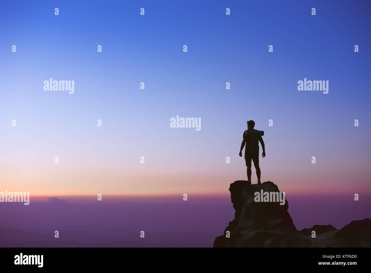 La silhouette de l'homme au sommet de montagne sur fond de ciel de coucher du soleil Banque D'Images