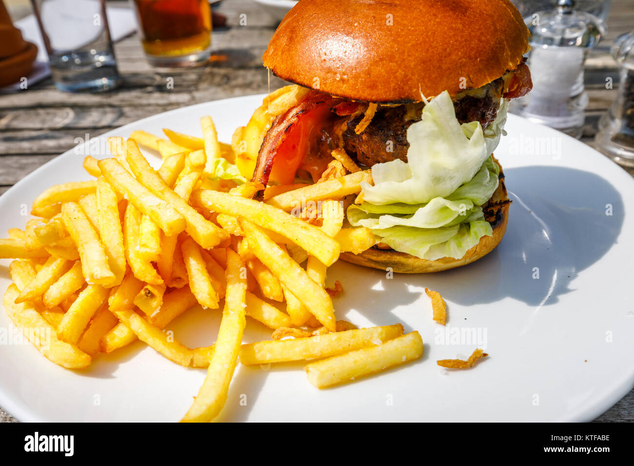 Obésité : pub typiquement britannique : un beefburger en un petit pain avec du fromage et du bacon et un tas de frites dorées, burger et frites sur une assiette blanche Banque D'Images