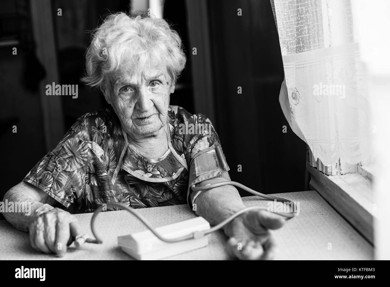 Une femme âgée mesures pression artérielle. Le noir et blanc. Banque D'Images