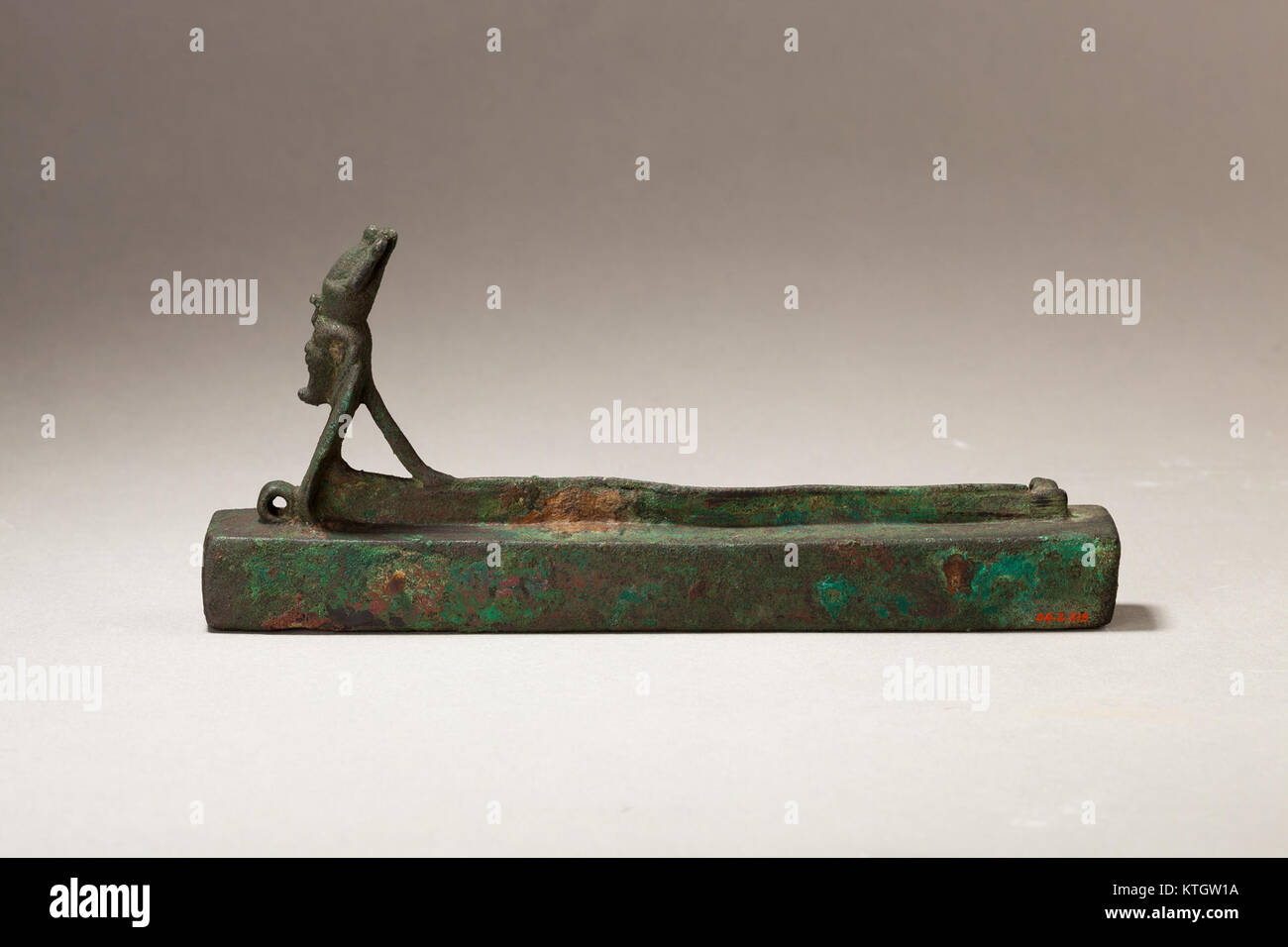 Cet artefact égyptien antique représente Atum, le Dieu créateur, sous la forme d'un cobra à tête humaine au-dessus d'une boîte contenant une momie animale, mettant en valeur l'iconographie religieuse égyptienne et les pratiques funéraires. Banque D'Images
