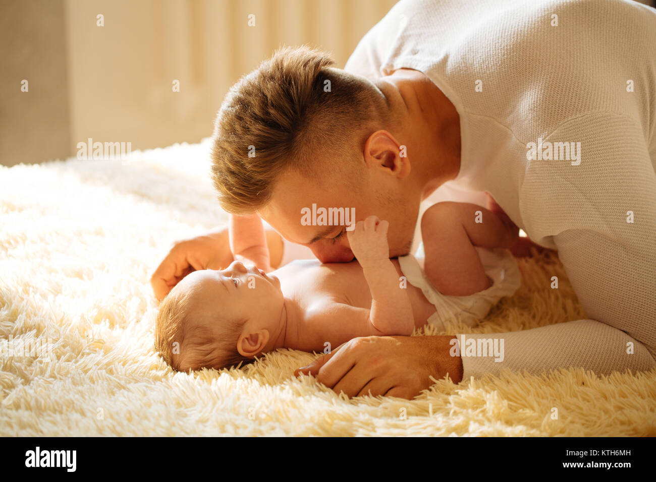 Père couché sur lit et tient son bébé Banque D'Images
