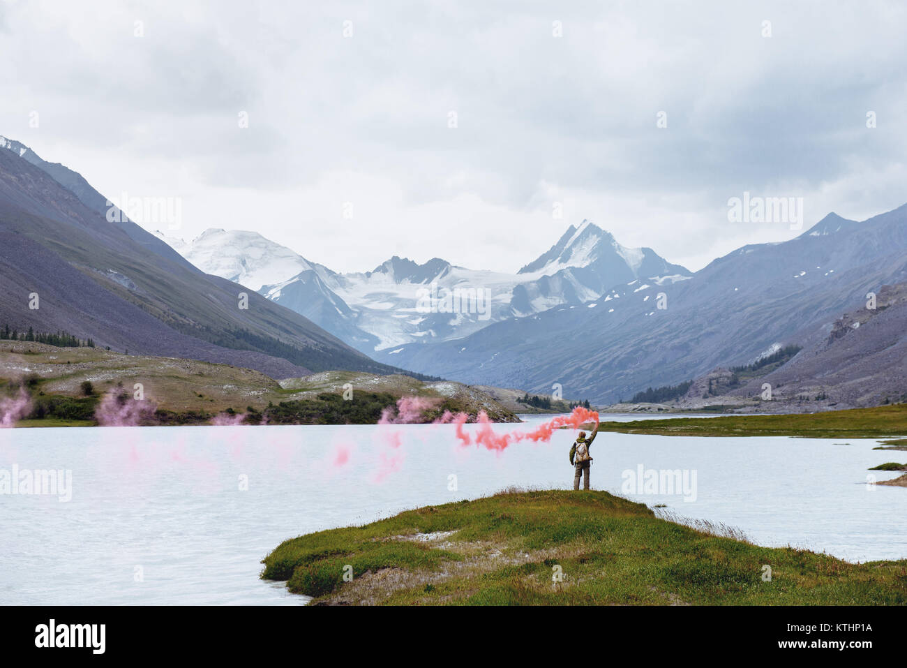 L'homme se tient avec signal rouge feu sur fond de beau lac de montagne et glacier Banque D'Images