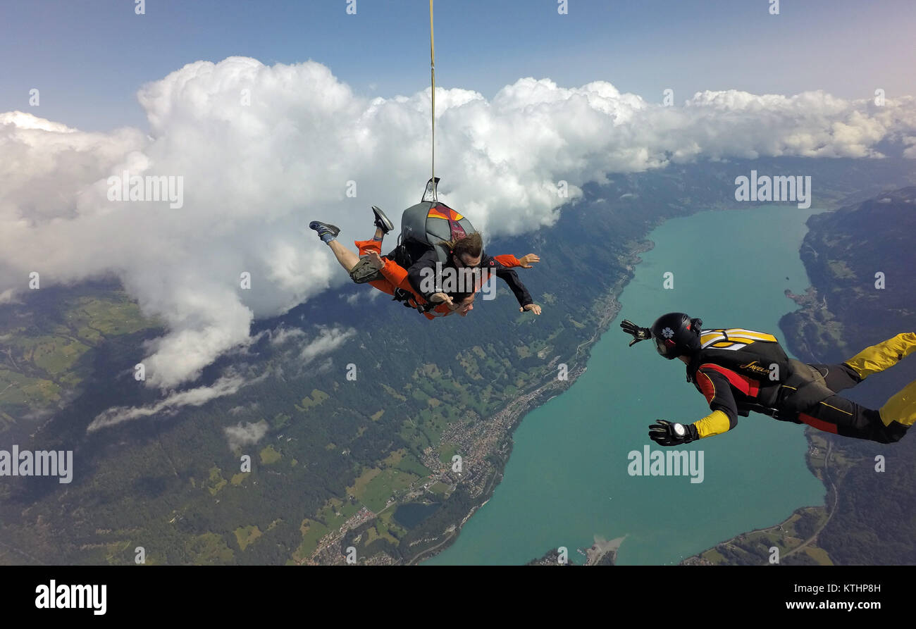 Cette skydiving tandem couple, plus le cavalier fun qui profitent du grand paysage, au-dessus de la magnifique région du lac et montagne. Vérifier leurs smileys ! Banque D'Images