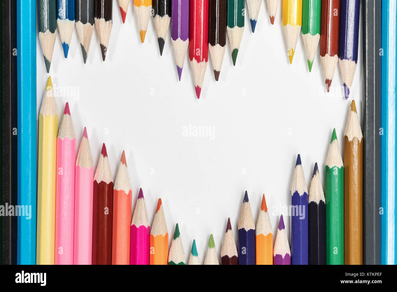 Crayons de couleur sur papier blanc bordée en forme de cœur Banque D'Images Crayons de couleur sur papier blanc bordée en forme de cœur Banque D'Images
