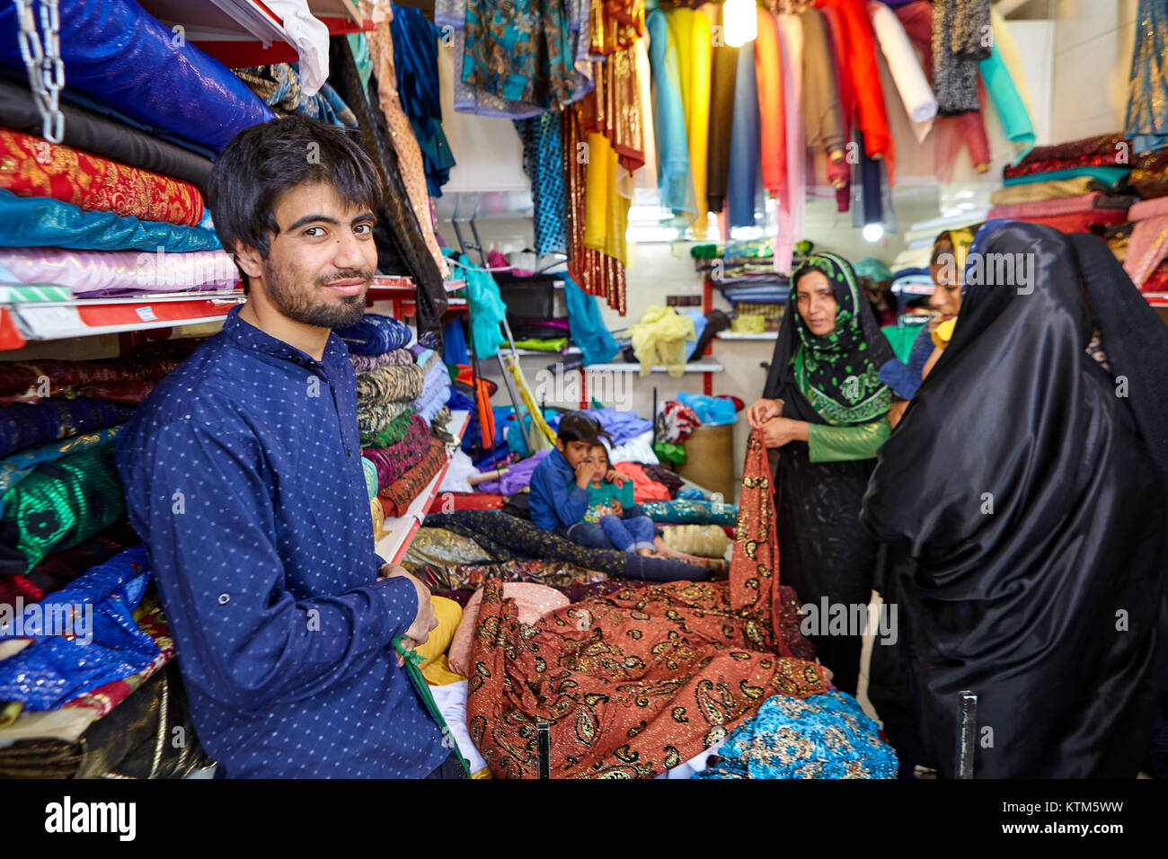 Yazd, Iran - avril 22, 2017 : un jeune négociant textile iranien dans le bazar, l'attente pour les femmes musulmanes pour choisir les produits pour l'achat. Banque D'Images