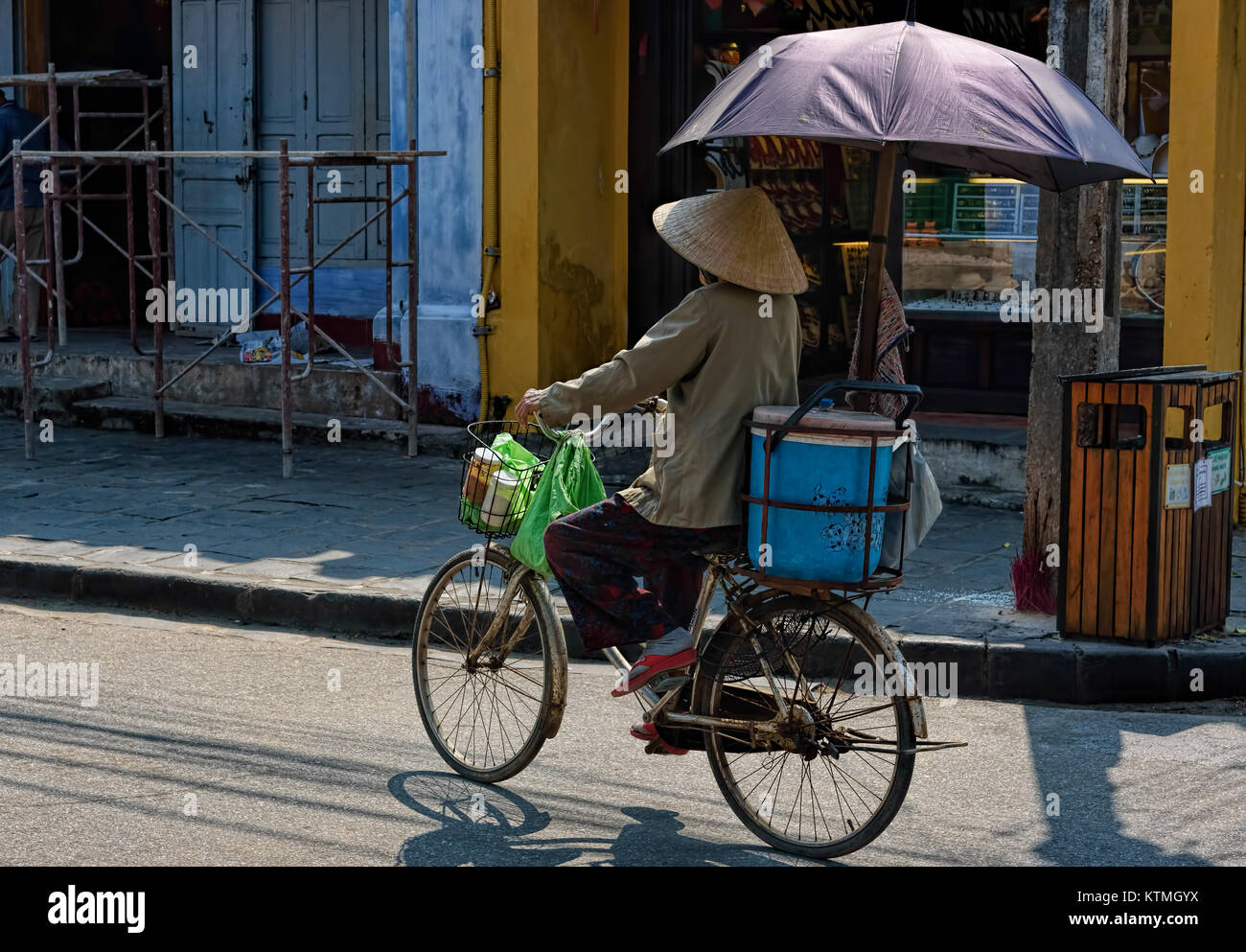 Woman riding a bike avec parapluie dans les rues de Hoi An, Vietnam Banque D'Images