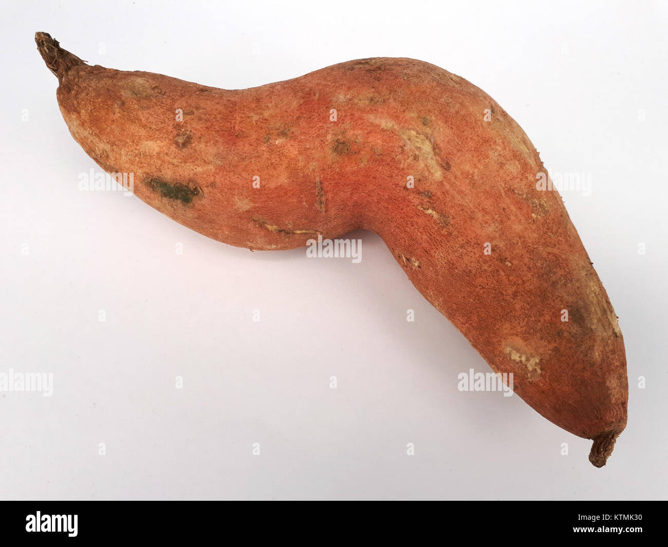 Cette image montre une patate douce courbée, capturée en 2017. La pomme de terre semble tordue, soulignant sa forme unique et naturelle. Les patates douces sont souvent connues pour leurs qualités nutritives et leur polyvalence en cuisine. Banque D'Images