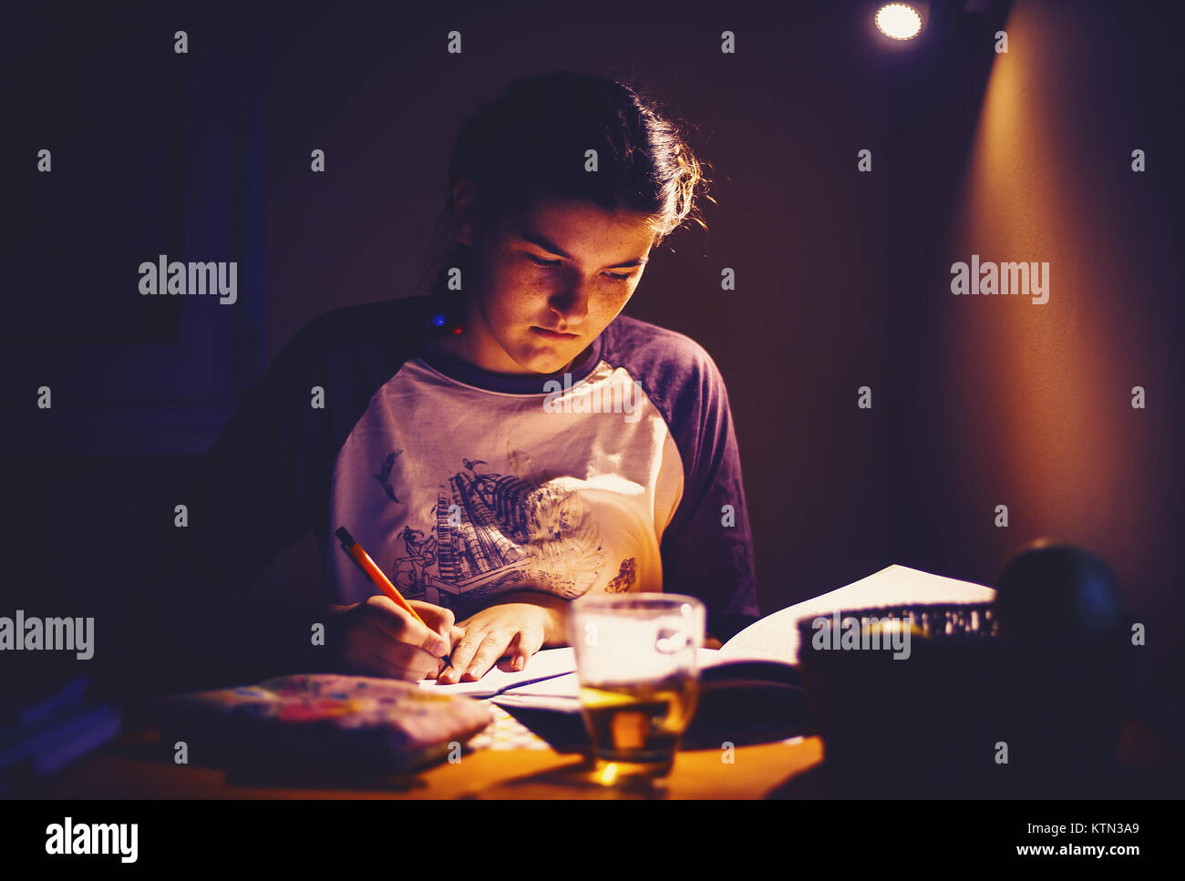 Jeune fille est à faire des devoirs à la maison, éclairage intéressants détails. Banque D'Images